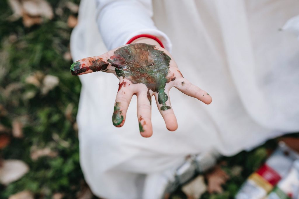 girl sitting on grass and showing dirty hand